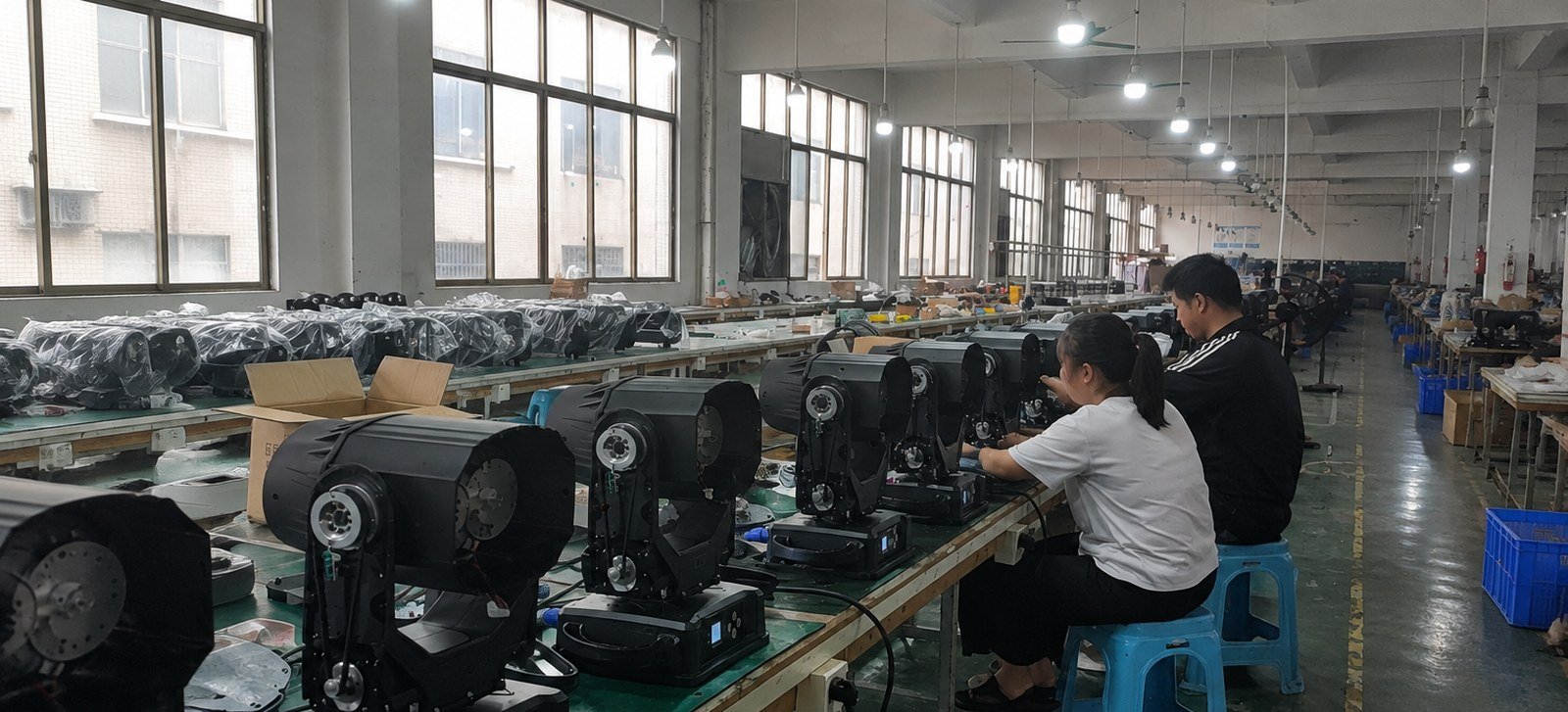 Technicians assembling moving-head fixtures on the GOGFITS factory bench